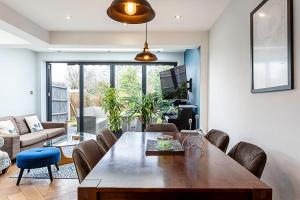 a living room with a large wooden table and chairs at Modern and Spacious Colliers Wood Home in London