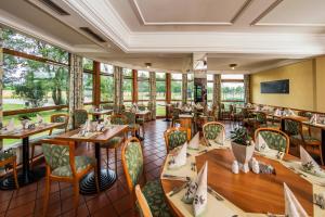 a restaurant with tables and chairs and windows at Johannesbad Thermalhotel Ludwig Thoma in Bad Füssing