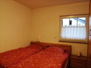 a bedroom with a red bed and a window at Ferienwohnung Blumenparadies in Nettersheim