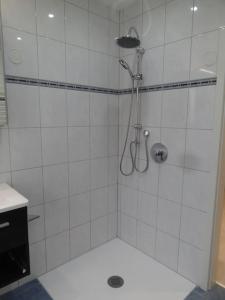 a shower in a white tiled bathroom at Idyllisch gelegene EG-Wohnung m. 3 Schlafzimmern in Bünde