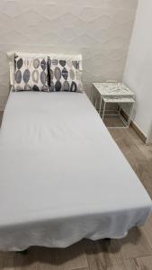 a white bed with pillows and a side table at CASA VACACIONAL in Pinto