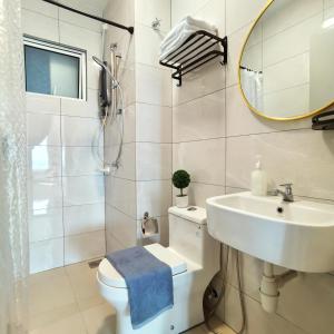 een badkamer met een wastafel, een toilet en een spiegel bij Amber Cove Seaview I MUJI 2BR I Game Room I 3-9pax in Melaka