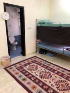 a room with a rug on the floor and a bathroom at Heritage Hostel Muscat in Muscat
