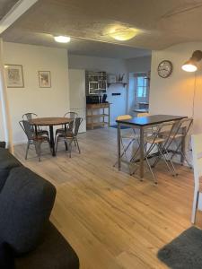 a living room with two tables and chairs and a kitchen at Hyggeligt gæstehus in Kjellerup