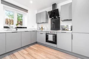 a white kitchen with white cabinets and a wooden floor at The Marsons Collection - 2 Bedrooms Apartment - Balcony - Secure Parking - 1MC in Birmingham