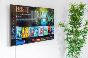 a flat screen tv hanging on a wall with two plants at The Marsons Collection - 2 Bedrooms Apartment - Balcony - Secure Parking - 1MC in Birmingham