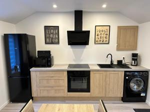 a kitchen with a black refrigerator and a dishwasher at Chez FanF & Nanie - Maison De Vacances Tout Confort - Proche Plages du Débarquement in Isigny-sur-Mer +8 photos