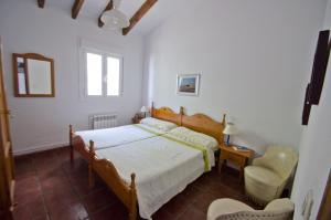 een slaapkamer met een bed en een stoel bij Cortijo Bellavista in Cómpeta