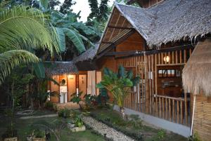 a house with a thatched roof and a garden at Loboc Cool River Resort in Loboc