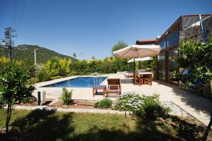 a backyard with a pool and an umbrella and a table and chairs at Kilim Kaya Villas in Kınalı