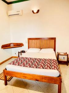 a bedroom with a bed with a wooden headboard at LE NOUVEL EDEN in Toliara