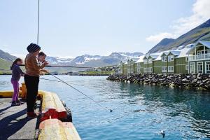 a couple of people standing on a dock holding a fishing line at Siglo Hotel by Keahotels in Siglufjörður