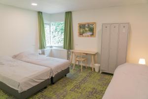 a bedroom with two beds and a desk and a table at de Admiraal in Den Helder