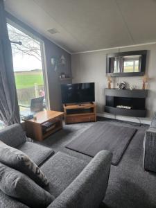 ein Wohnzimmer mit einem Sofa und einem TV in der Unterkunft Hesket caravan park Plot Number 7 STRICTLY NOT FOR COMMERCIAL USE in High Hesket