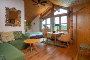 a living room with a green couch and a table at Landhaus Charivari Sommer-Hörnerbahnen kostenlos in Bolsterlang