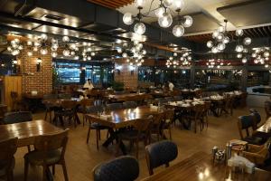 a restaurant with wooden tables and chairs and chandeliers at Mihman Hotel in Tuzla