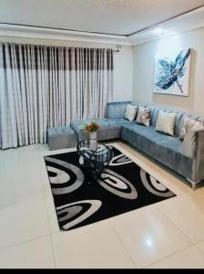 a living room with a blue couch and a table at Emerald Suite 3-Bed House in Harare in Harare