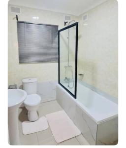 a bathroom with a toilet and a tub and a sink at Beautiful 3-Bed House in Harare in Harare
