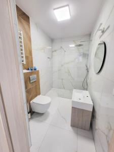 biała łazienka z toaletą i umywalką w obiekcie Hotel Gorzelanny i Apartamenty Dźwirzyno w Dźwirzynie