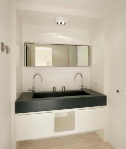 uma casa de banho com um lavatório e um espelho em Sterflat 97 em Egmond aan Zee