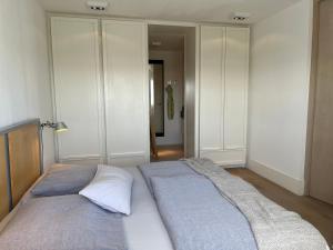 uma cama grande num quarto com armários brancos em Sterflat 97 em Egmond aan Zee