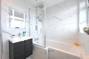 La salle de bains blanche est pourvue d'un lavabo et d'une douche. dans l'établissement SUPERB 4 BEDROOM FLAT in THE HEART OF CAMDEN TOWN, à Londres