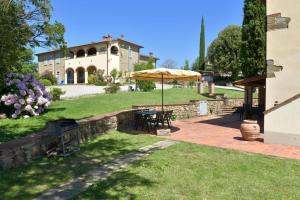 a patio with a table and an umbrella in front of a house at Agriturismo Borgo Sant'Ercolano in Ciggiano