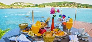 a table with food and drinks and a view of the water at Hotel Ferradura Private in Búzios