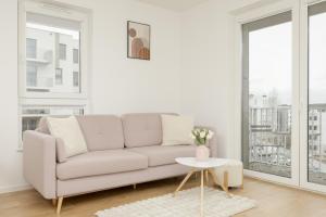 ein weißes Wohnzimmer mit einem Sofa und einem Tisch in der Unterkunft Bright Pastel Apartment with Desk for Remote Work, Balcony and Parking by Renters in Danzig