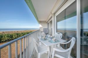 a balcony with a table and chairs and the ocean at Appartement face mer pour 4 à Saint Brévin L’Océan in LʼErmitage
