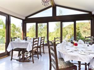 uma sala de jantar com mesas, cadeiras e janelas em Hill Crest Country Guest House em Newby Bridge