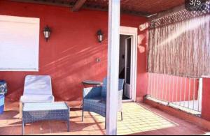 セビリアにあるSEVILLA ROOM, VIEW TO THE CITYの椅子とテーブルと赤い壁のあるポーチ