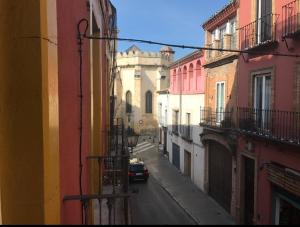 セビリアにあるSEVILLA ROOM, VIEW TO THE CITYの細い道を車が走り、建物が並ぶ
