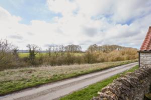 a dirt road next to a stone wall at Valley View Farm Holiday Cottages in Helmsley