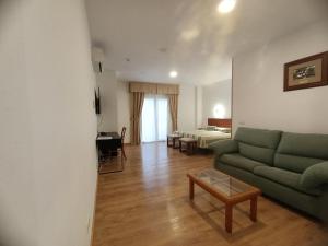 a living room with a green couch and a bed at La Luna Blanca in Torremolinos