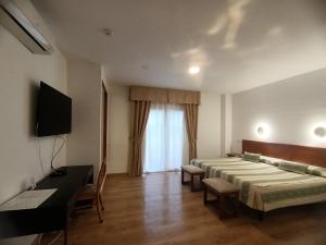 a bedroom with two beds and a desk and a television at La Luna Blanca in Torremolinos