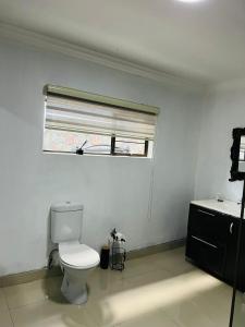 a white bathroom with a toilet and a window at Le Bamboo Guest House And Boat Cruise in Hartbeespoort