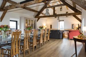 a dining room and living room with a long table and chairs at The Barn at Plas Ashpool Sleeps 8 in Llandyrnog