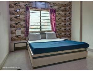 a bed in a room with a window and a blue mattress at Hotel Shiv Sadan, Somnath in Somnath