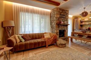 a living room with a brown couch and a stone fireplace at Captivating 3-Bed Villa in Brezovica Ski Centre in Brezovica