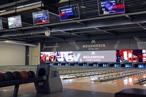 a bowling alley with many lanes and televisions at Hotel Meilenstein in Langenthal