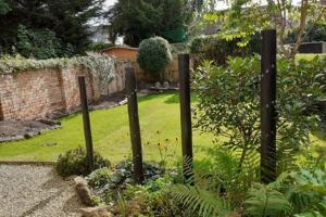 um jardim com uma cerca no meio de um quintal em Emerald Suite Moseley Mews by StayStaycations em Birmingham