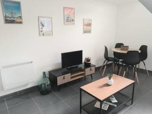 ein Wohnzimmer mit einem TV, einem Tisch und Stühlen in der Unterkunft L'Erissy D'Acqs in Dax
