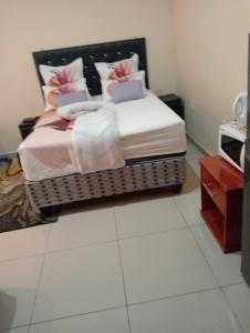 1 dormitorio con 1 cama con almohadas rosas y blancas en Rizhatchguest en Mafikeng
