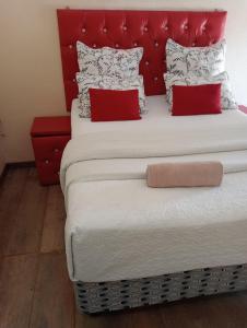 a large bed with a red headboard and red pillows at Rizhatchguest in Mahikeng