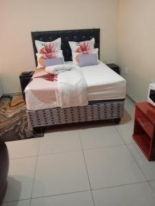 1 dormitorio con 1 cama grande con almohadas rosas y blancas en Rizhatchguest, en Mahikeng