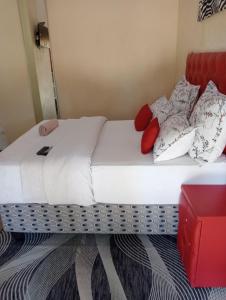 a bed with white sheets and red pillows on it at Rizhatchguest in Mahikeng