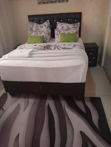 1 dormitorio con 1 cama grande y edredón blanco y negro en Rizhatchguest en Mafikeng