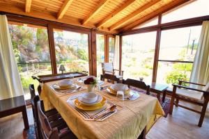 a dining room with a table and chairs and windows at Kilim Kaya Villas in Kınalı