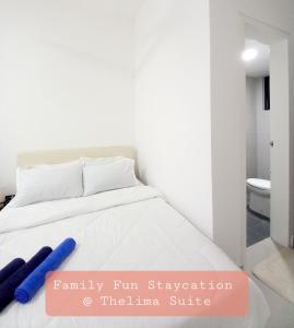 a white bed with two blue pillows on it at Family Fun Staycation @ Thelima Suite in Kajang